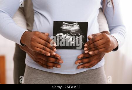 Black couple holding ultrasound image en face de femme belly Banque D'Images