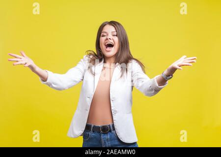 Portrait de Ravi beautiful brunette woman veste en jeans et élever les mains dans un geste de bienvenue de crier de joie, ravis de vous voir et d'aller à Banque D'Images