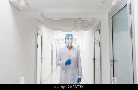 Jeune femme médecin médical de protection en passant par l'usure du corridor laboratoire vide Banque D'Images