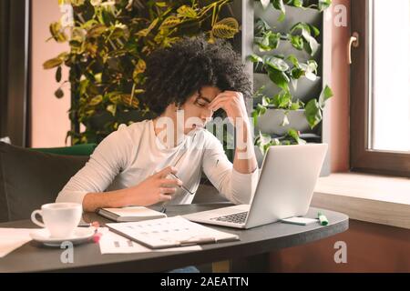 Désespéré a souligné man sitting in cafe with laptop Banque D'Images