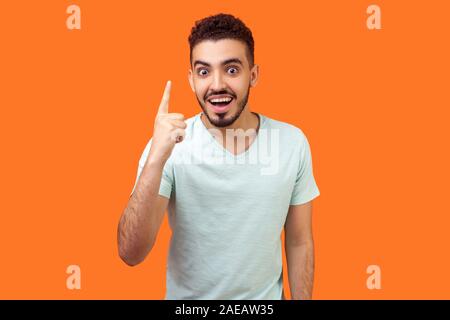 Portrait de l'homme inspiré beau brunette avec barbe en t-shirt blanc montre de l'index et à la recherche sur l'idée d'étonnement soudain, s'solution. je Banque D'Images