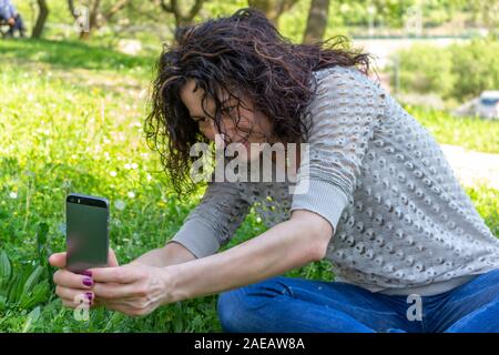 Jeune Femme prenant une photographie à une fleur avec l'iphone Banque D'Images