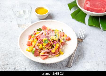 Hawaiian Tropical thon salade de mangue de tahiti sur plaque blanche on tropical monstera leafe Banque D'Images