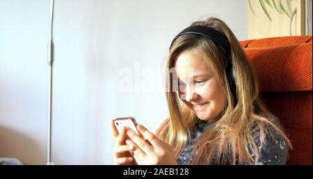 Fille utilise la technologie moderne. Petite fille jouant sur un téléphone cellulaire. L'enfant passe son temps libre avec la technologie moderne. Banque D'Images