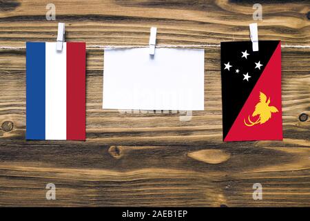 Drapeaux suspendus des Pays-Bas et de la Papouasie-Nouvelle-Guinée attaché à la corde avec des pinces à linge avec de l'espace de copie sur papier blanc sur fond de bois.Diplomat Banque D'Images