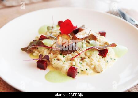 Risotto aux cèpes poêlés sur plaque de porcelaine blanc, teinté de droit Banque D'Images