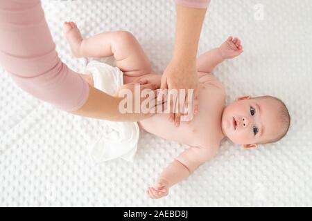 Massage pour bébé. Female therapist en massant doucement bébé nouveau-né garçon. Appliquer une lotion pour le corps de la mère à son enfant bébé garçon. Massage des nouveau-nés (top view background Banque D'Images