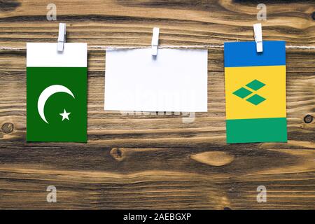 Drapeaux suspendus du Pakistan et à Saint Vincent et les Grenadines attaché à corde avec pinces à linge avec copie espace blanc sur papier note sur zone en bois Banque D'Images