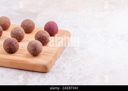 Des boules d'énergie Cacao Végétalien Premières sur plateau en bois sur fond de marbre blanc Banque D'Images