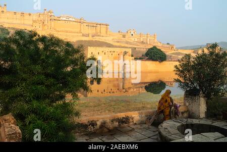 Scène rurale avec femme dans la région de sari en Cour arrière donnant sur Fort Amber baigné de soleil du matin à Jaipur, Rajasthan, Inde. Banque D'Images