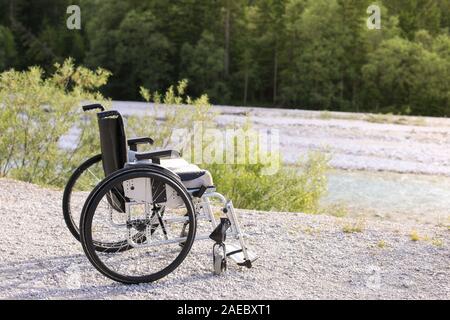 Fauteuil roulant vide debout dans un parc sur le chemin de marche Banque D'Images