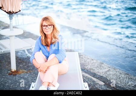 High angle shot pleine longueur de belle mature woman sitting on bain de soleil et se détendre. Banque D'Images