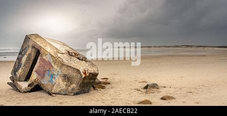 La plage de la Torche en Bretagne en hiver. Les ruines d'un ancien bunker allemand WWII semblent échoués sur la plage, sous un ciel de nuages menaçants Banque D'Images