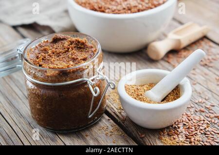 Pot en verre de matières organiques à partir de la pâte de graines de lin et de petit mortier de linseeds broyée en poudre sur table en bois. Banque D'Images