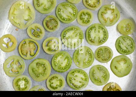 Solanum lycopersicum. Tranches de tomates vertes immatures n une poêle. Banque D'Images