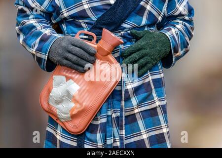 La pauvreté en carburant : un retraité vulnérable en robe de chambre et gants de laine mal assortis tente de rester au chaud alors que les factures de carburant et les coûts de la vie montent en flèche au Royaume-Uni Banque D'Images