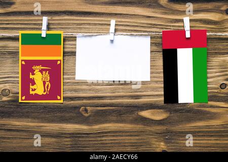 Drapeaux suspendus de Sri Lanka et Emirats Arabes Unis attaché à la corde avec des pinces à linge avec de l'espace de copie sur papier blanc sur fond de bois.Diplom Banque D'Images