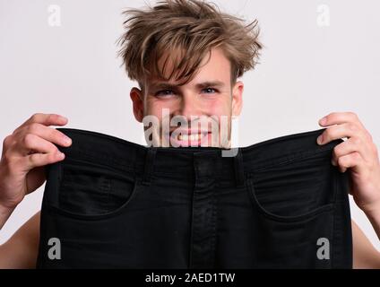 Guy avec visage heureux isolé sur fond gris clair. La taille de la mode et de concept. Avec l'athlète de cheveux en désordre et large sourire. L'homme est titulaire jean noir de grande taille XXL. Banque D'Images