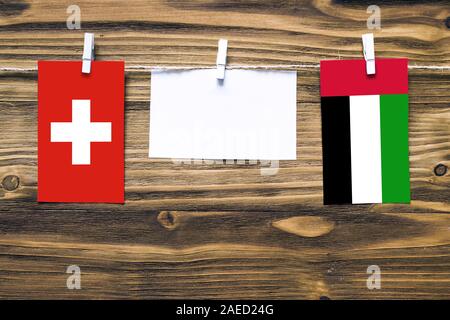 Drapeaux suspendus de la Suisse et les Émirats arabes unis attaché à la corde avec des pinces à linge avec de l'espace de copie sur papier blanc sur fond de bois.Dipl Banque D'Images