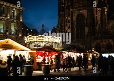 Strasbourg, France - Dec 20, 2016 : scène de nuit avec rangée de stalles du marché chalets avec plusieurs jouets et souvenirs en vente à la place de la Cathedrale et merry-go-round carousel Banque D'Images