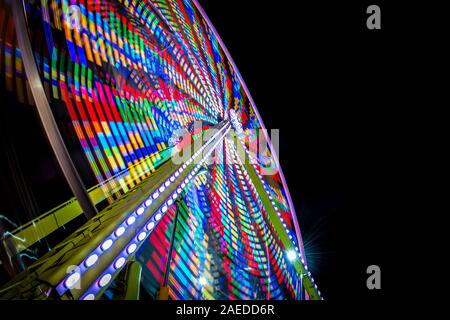 Une grande roue, illuminé par un éclairage LED multicolore fonctionne de nuit. Banque D'Images