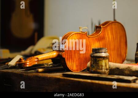 Maître luthier violon fabricant vernissage d'un luth à cordes de violon fait à la main comme touche finale pour terminer sa création dans son atelier de Cremona, Lombardie Banque D'Images