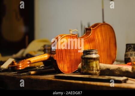 Maître luthier violon fabricant vernissage d'un luth à cordes de violon fait à la main comme touche finale pour terminer sa création dans son atelier de Cremona, Lombardie Banque D'Images