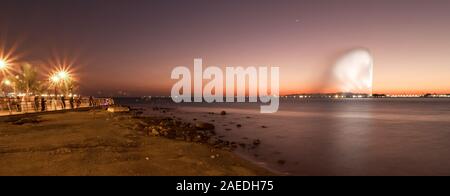 L'arabe les gens debout à la Corniche du Sud à Jeddah, Arabie saoudite, regardant le King Fahd's Fountain et le magnifique coucher de soleil colorés et Banque D'Images