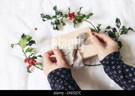 Closeup of woman's hand holding et l'emballage boîte-cadeau. Hiver Noël design. Concept d'artisanat. Style Féminin stock photo. Arrière-plan flou avec Banque D'Images