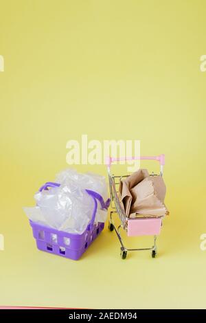 Sacs de polyéthylène et de papier dans un panier sur un fond jaune Banque D'Images