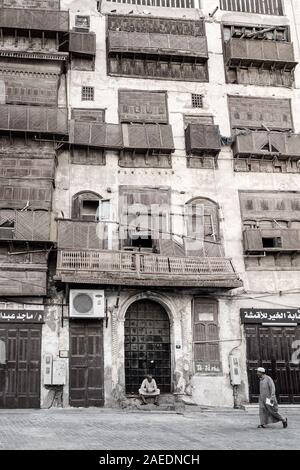 Senior arabe assis sur les marches devant la porte d'une maison de ville de corail dans le quartier historique Al Balad à Jeddah, Arabie saoudite, Arabie Saoudite Banque D'Images