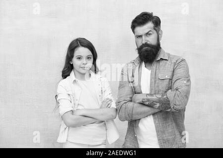 Appel occasionnel. Petite fille et l'homme barbu dans un style décontracté sur fond gris. Look décontracté de père et fille. Enfant mignon et brutale en gardant les bras croisés en hippie vêtements décontractés. Banque D'Images