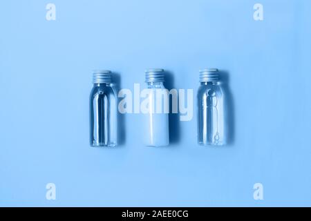 Mise à plat de trois petites bouteilles de maquettes avec les produits cosmétiques spa dans le quartier branché de couleur bleue. Femmes beauté et salon de beauté concept. Couleur de la Banque D'Images