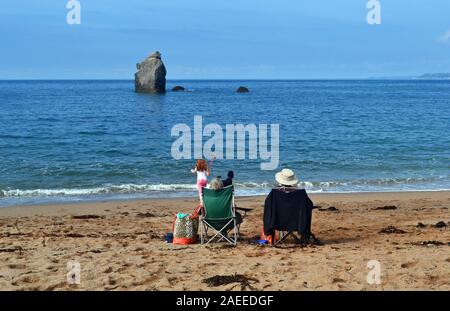 Couple assis sur des chaises sur la plage, à côté de la mer, à South Milton Sands, Devon, UK Banque D'Images