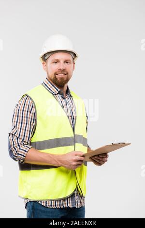 Cheerful young contremaître ou d'ingénieur avec presse-papiers dans l'isolement permanent Banque D'Images