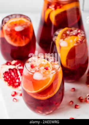 Sangria d'hiver sur fond de marbre blanc. Jugful de sangria et verres avec tranche d'orange et la grenade. L'espace pour copier du texte ou dessin. La verticale. Banque D'Images