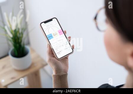 Part of contemporary businesswoman holding smartphone avec organigramme Banque D'Images