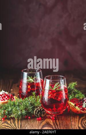 L'alimentation de vœux de Noël et du Nouvel An, la composition. Deux verres de boisson grenade entouré des branches de pins, bordeaux bordeaux fond de béton. Clo Banque D'Images