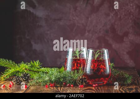 L'alimentation de vœux de Noël et du Nouvel An, la composition. Deux verres de boisson grenade entouré des branches de pins, bordeaux bordeaux fond de béton. Clo Banque D'Images