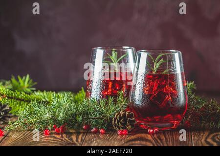 L'alimentation de vœux de Noël et du Nouvel An, la composition. Deux verres de boisson grenade entouré des branches de pins, bordeaux bordeaux fond de béton. Clo Banque D'Images