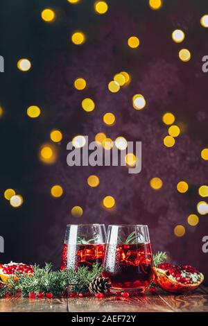 L'alimentation de vœux de Noël et du Nouvel An, la composition. Deux verres de boisson grenade entouré des branches de pins, bordeaux bordeaux avec fond en béton Banque D'Images