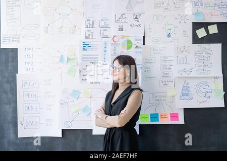 Les jeunes femmes économiste avec bras croisés par permanent tableau noir Banque D'Images