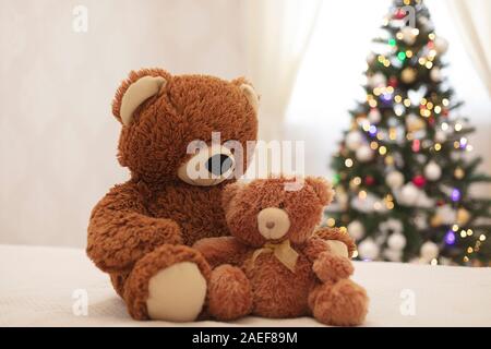 Joyeux Noël ! Les jouets d'ours en grands et petits sont assis sur le canapé dans le contexte de l'arbre de Noël. Focus sélectif. Banque D'Images