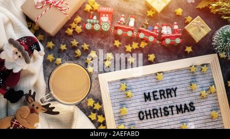 Une tasse de café chaud en hiver avec texte Joyeux Noël sur lettre , ornement de Noël décorations et boîte-cadeau sur la table pour Noël ba Banque D'Images