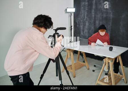 Guy en flexion casualwear devant une caméra vidéo pendant le tournage d'homme vlogge Banque D'Images