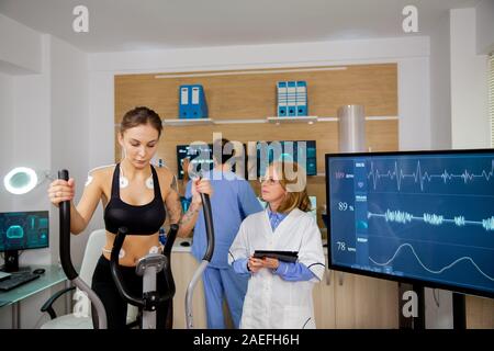 Faire de l'athlète féminine de l'effort physique et pas-à-pas de médecin avec le comprimé dans la main poursuit son. Les tests de sport Banque D'Images