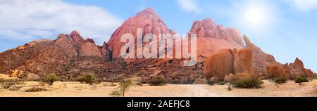 Spitzkoppe de montagnes vue panoramique sur le ciel bleu, des nuages et un soleil éclatant, l'arrière-plan la montagne paysage panorama des roches rouges en Namibie, Afrique Banque D'Images