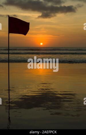 Silhouettes d'un drapeau sur la plage au coucher du soleil, Double Six Beach, destination de surf populaire Banque D'Images