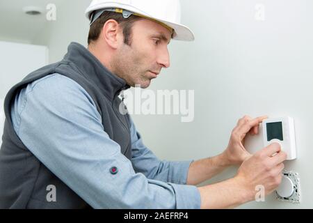 Travailleur homme pose du thermostat Banque D'Images