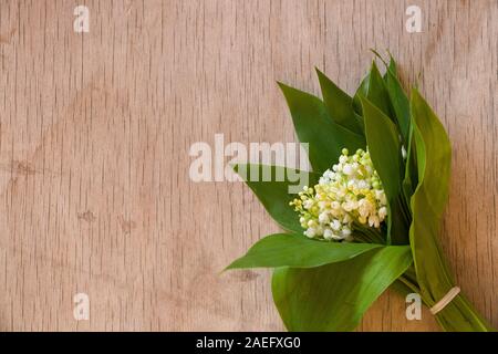 Bouquet de Lys de la vallée. Bouquet de Lys de la vallée sur le tissu blanc et plancher en bois rustique. Arrière-plan horizontal Banque D'Images